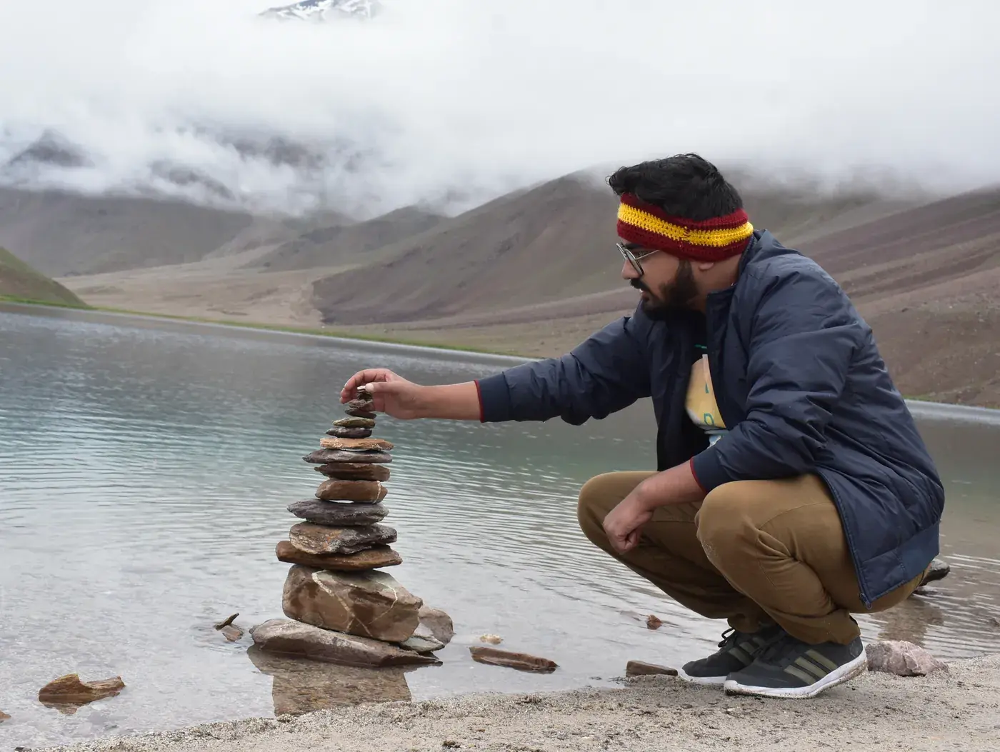 Stacking a cairn of flat stones at the edge of Chandratal