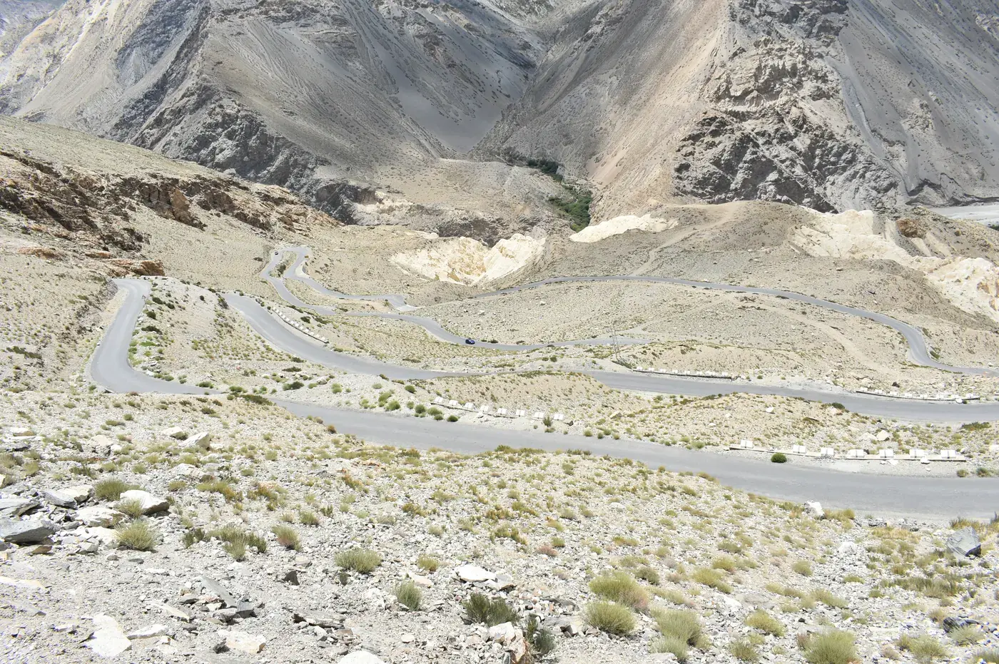 Hairpin loops of road cut into a bare grey mountainside above the Sutlej