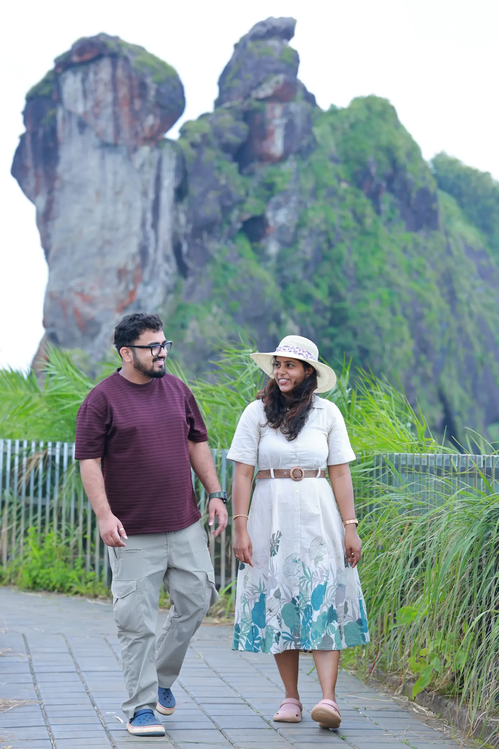 A couple walking a paved path below the rock pinnacles of Illikal Kalu